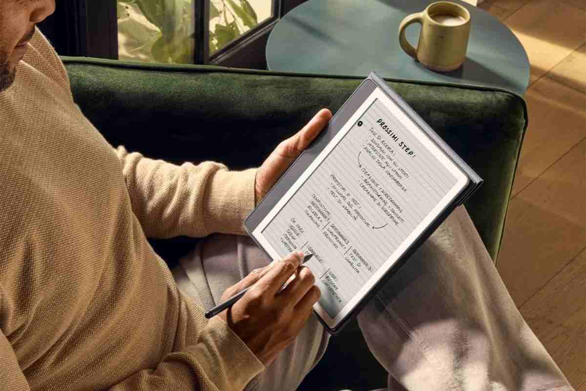 uomo seduto su poltrona scrive su kindle con penna