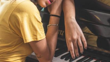 Una pianista con la maglia gialla appoggiata al pianoforte