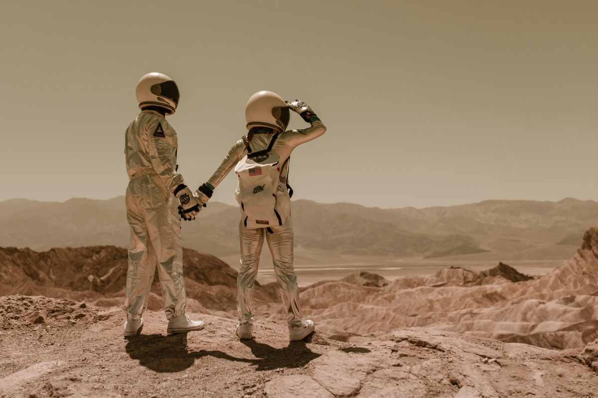 Due astronauti si tengono per mano su un pianeta alieno