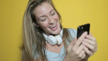 Una ragazza bionda sorride guardando lo smartphone