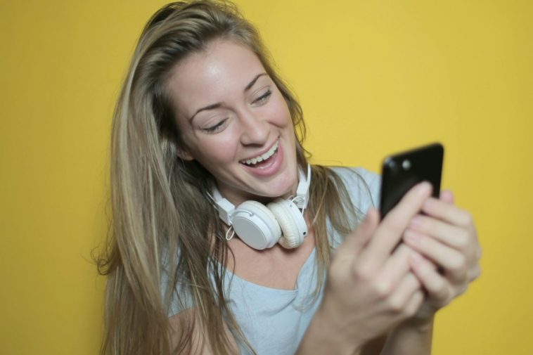 Una ragazza bionda sorride guardando lo smartphone