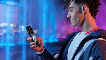 ragazzo che ha in mano lo smartphone honor 400 lite su sfondo blu e fucsia