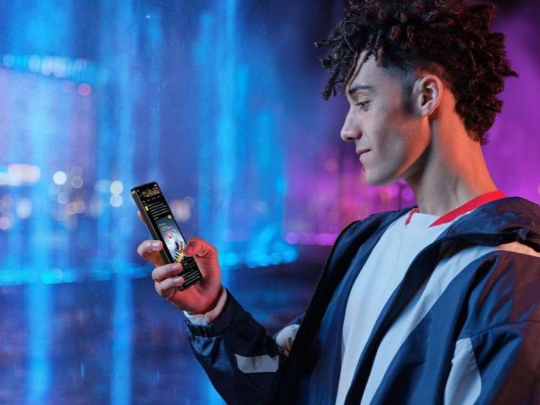 ragazzo che ha in mano lo smartphone honor 400 lite su sfondo blu e fucsia