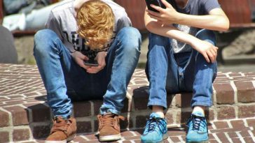 Due ragazzini piegati sui loro smartphone
