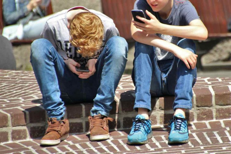 Due ragazzini piegati sui loro smartphone