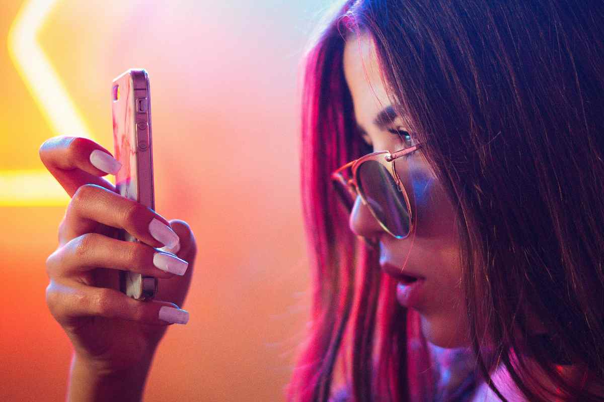 Una ragazza con gli occhiali da sole che guarda uno smartphone