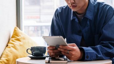 Un ragazzo seduto al tavolo di un bar che consulta un telefono