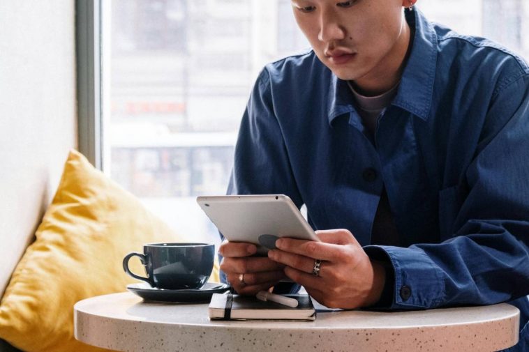 Un ragazzo seduto al tavolo di un bar che consulta un telefono