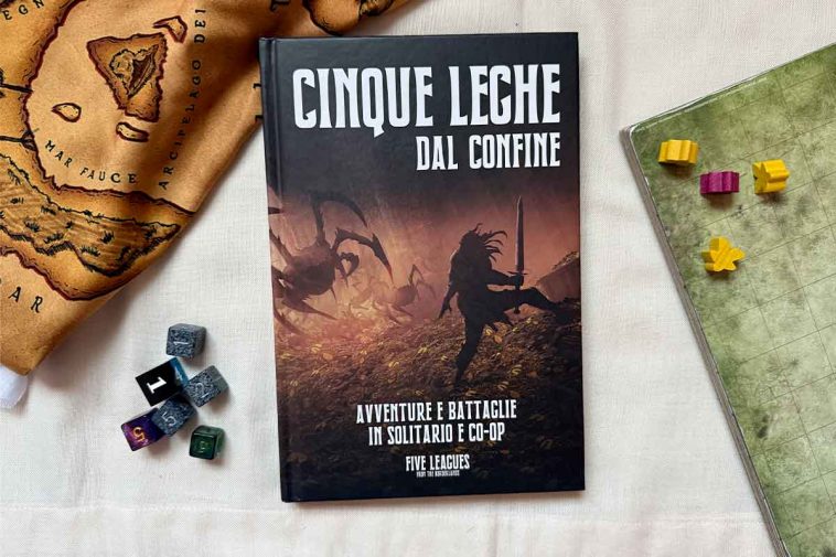 Manuale di Cinque Leghe dal Confine con miniature, dadi e mappe attorno