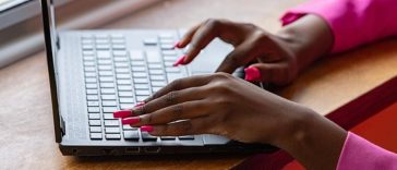 Una donna con le unghie rosse che batte al computer