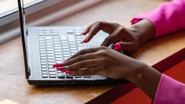 Una donna con le unghie rosse che batte al computer