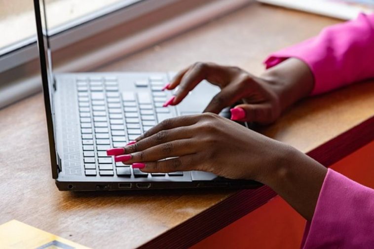 Una donna con le unghie rosse che batte al computer
