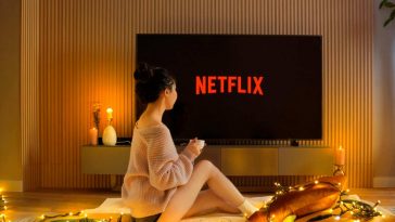 Una ragazza seduta a letto di fronte allo schermo con Netflix