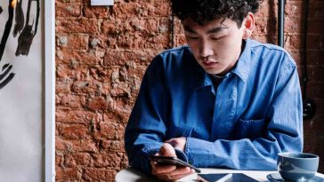 Un ragazzo seduto al tavolino di un bar che usa il telefonino