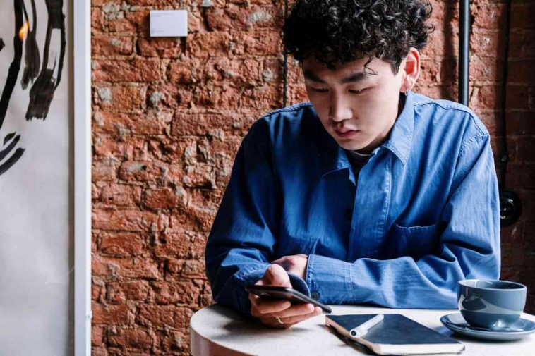 Un ragazzo seduto al tavolino di un bar che usa il telefonino