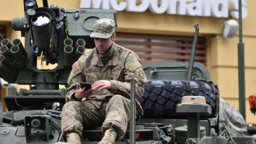 Un soldato seduto su un carrarmato fuori da un McDonalds