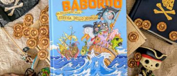 Il fumettogame Bestie a Babordo al centro di varie chincaglierie pirata: dobloni, bandiere, mappe