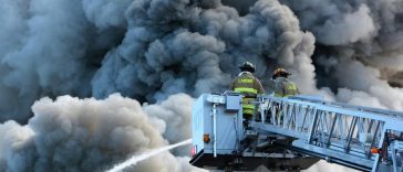 Dei vigili del fuoco su una gru circondati dal fumo