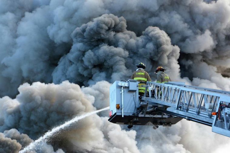 Dei vigili del fuoco su una gru circondati dal fumo