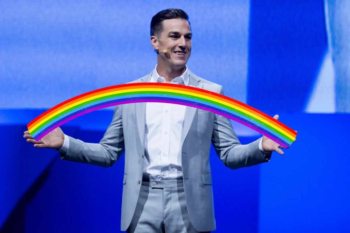 andrew wilson con giacca grgia che tiene in mano arcobaleno