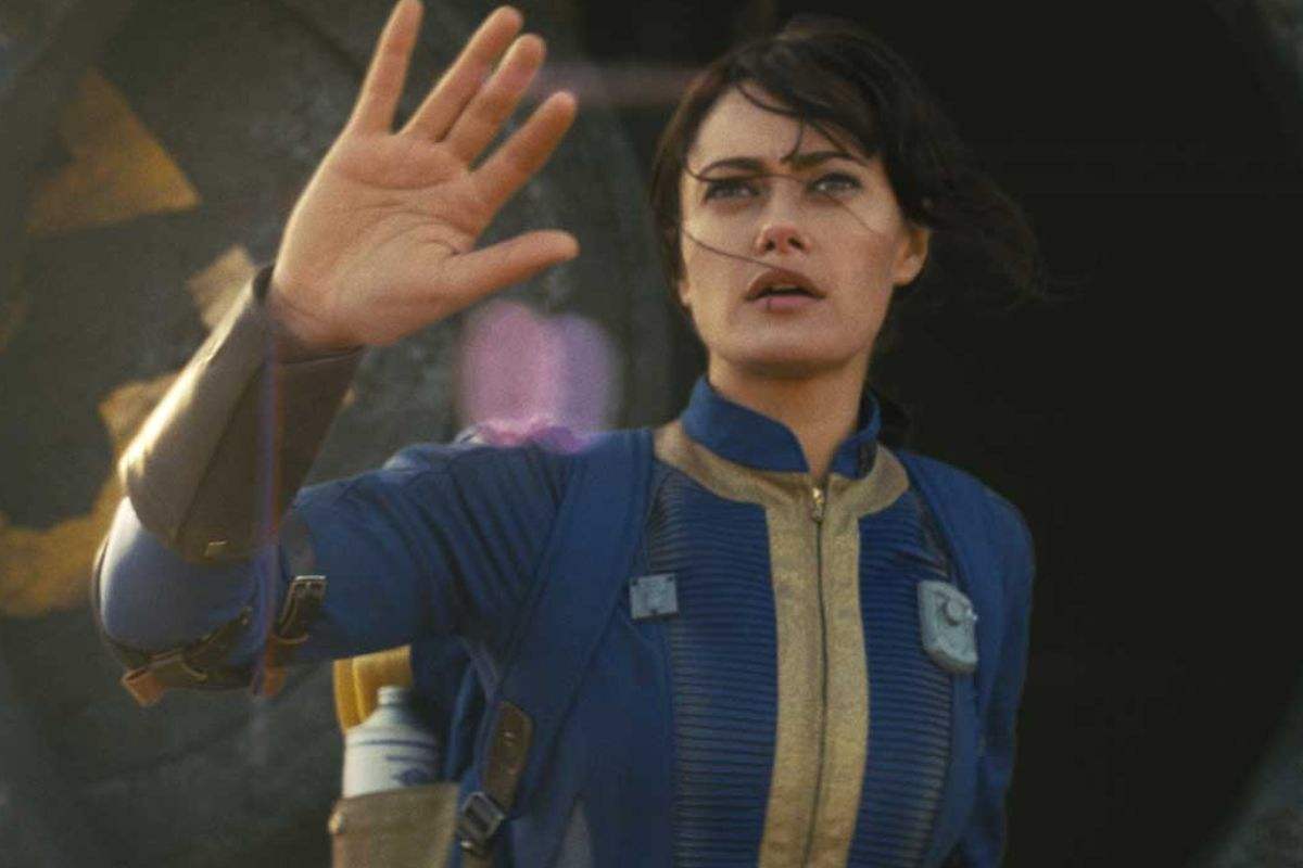 ragazza (ella purnell) con tuta blu e giala con mano alzata