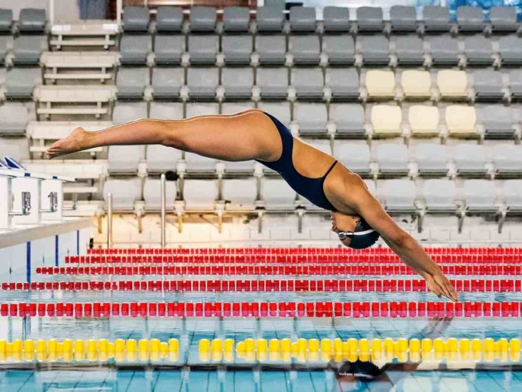 donna si getta in acqua con cuffia e occhalini