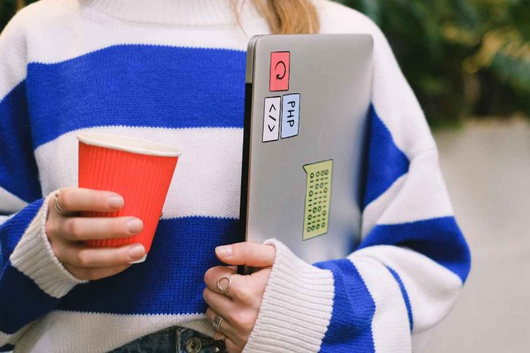 Una ragazza con un maglione a righe e un portatile sotto braccio
