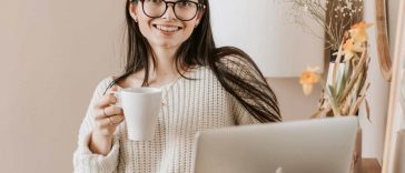 Una ragazza sorridente al computer con una tazza in mano