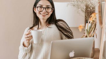 Una ragazza sorridente al computer con una tazza in mano