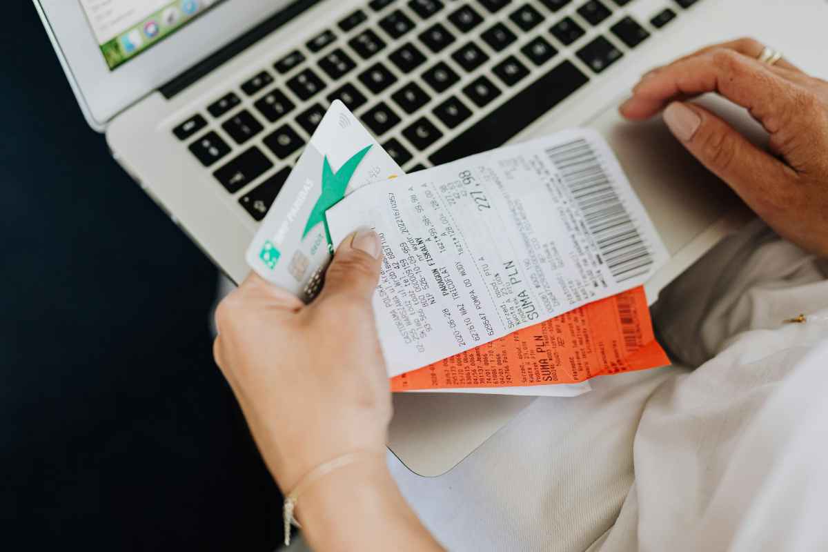 Un utente che fa acquisti online con un portatile, con degli scontrini in mano