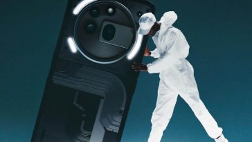 persona vestita di bianco che regge un Nothing Phone gigante su sfondo blu scuro