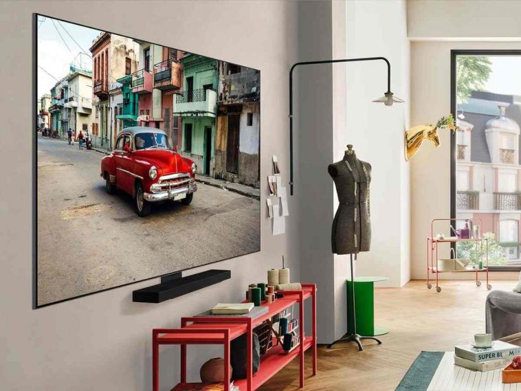 smart tv con immagine macchina rossa appesa in stanza con soundbar