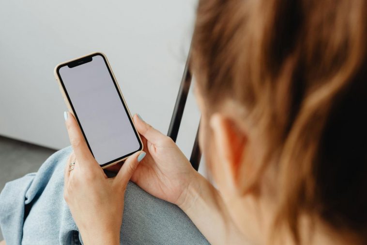 Una ragazza guarda lo schermo bianco di uno smartphone