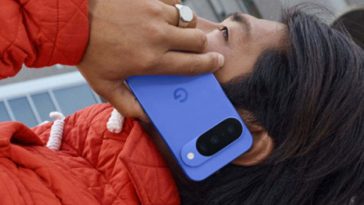 ragazzo sdraiato con cappotto rosso tiene all'orecchio google pixel 10 blu