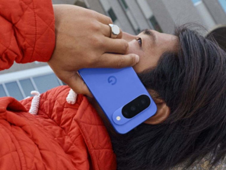 ragazzo sdraiato con cappotto rosso tiene all'orecchio google pixel 10 blu