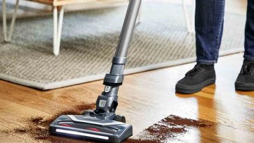 persona pulisce caffè da pavimento in legno con aspirapolvere elettrico