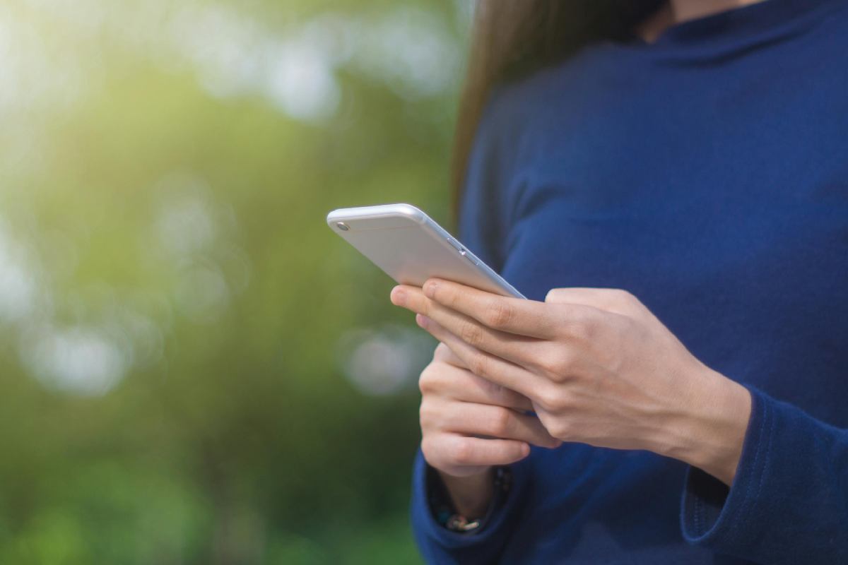 Una ragazza con un maglione blu che usa lo smartphone 
