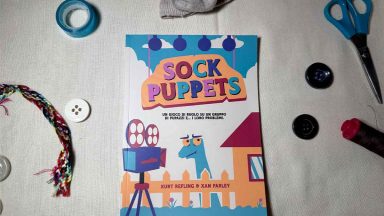 La copertina del manuale di Sock puppets circondato da bottoni, scotch, forbici e un calzino con gli occhietti