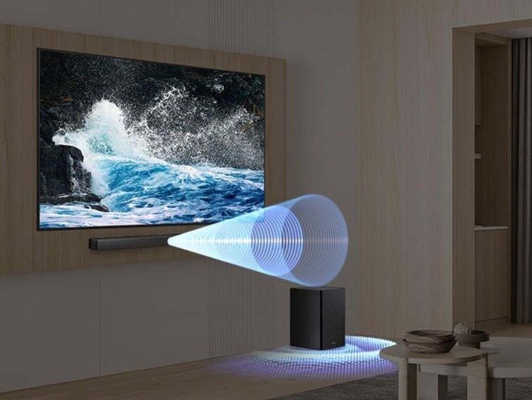 Samsung Soundbar HW che emette suono da sotto televisore appeso a parete