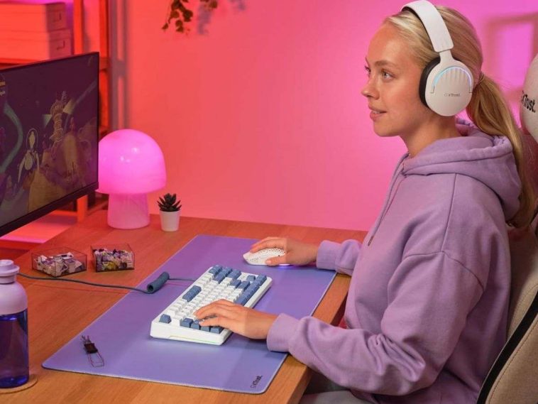 ragazza con cuffia bianca e felpa viola seduta a scrivania mentre usa tastiera meccanica