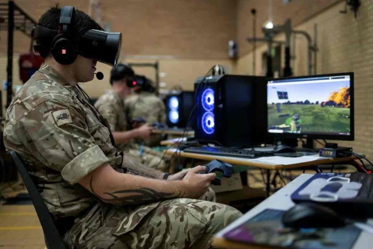 soldato con visore VR con cloche seduto davanti a schermo PC