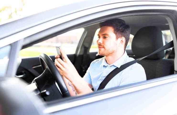 uomo in auto con smartphone