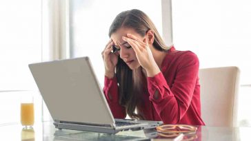 donna con le mani nei capelli che guarda il pc