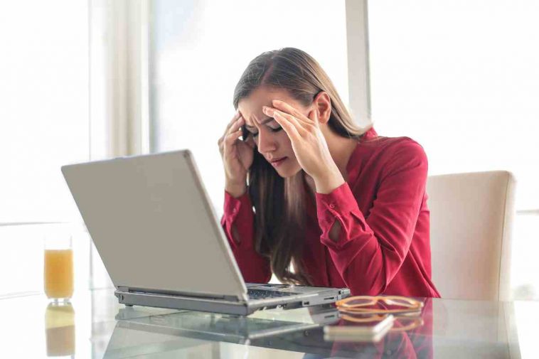 donna con le mani nei capelli che guarda il pc