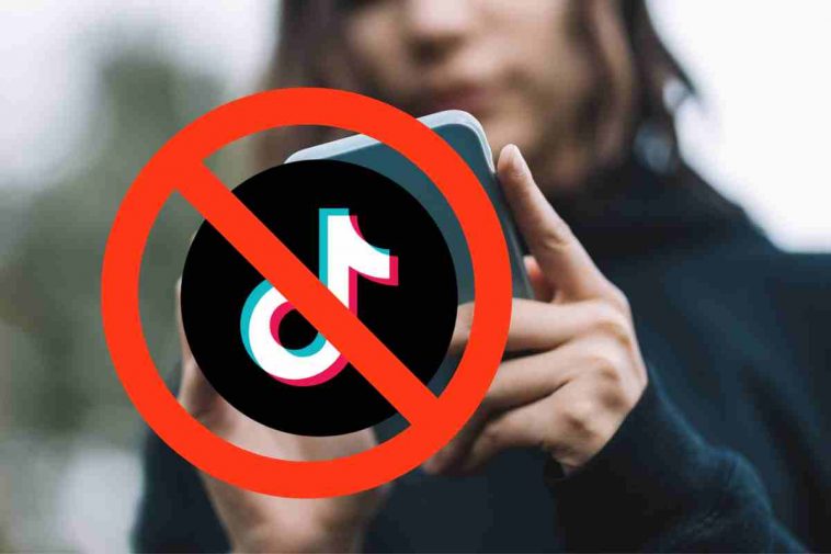 donna con smartphone e logo tiktok bannato