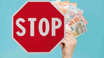 cartello stop e mano con soldi