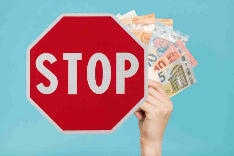 cartello stop e mano con soldi