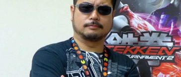 Harada uomo a braccia conserte con capelli neri e occhiali da sole