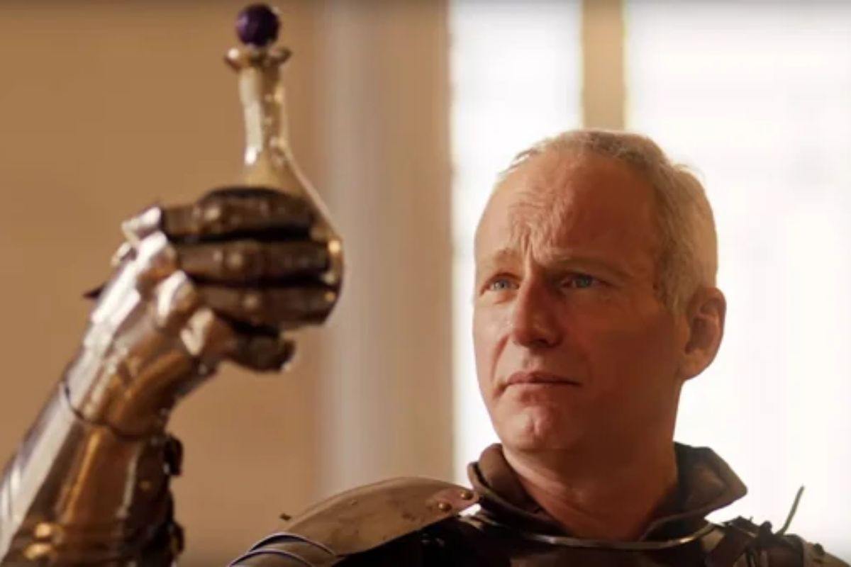 uomo con capelli bianchi, armatura medievale che tiene in mano un'ampolla di vetro