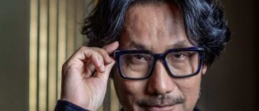 uomo giapponese con capelli brizolati che si tocca gli occhiali